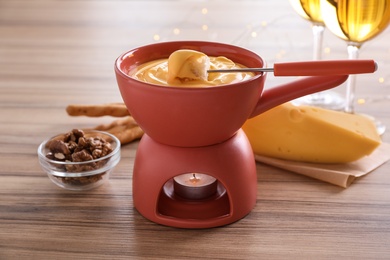 Photo of Pot with delicious cheese fondue and bread on table