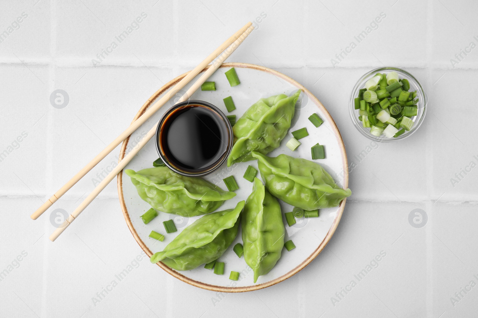 Photo of Delicious green dumplings (gyozas) served on white tiled table, flat lay