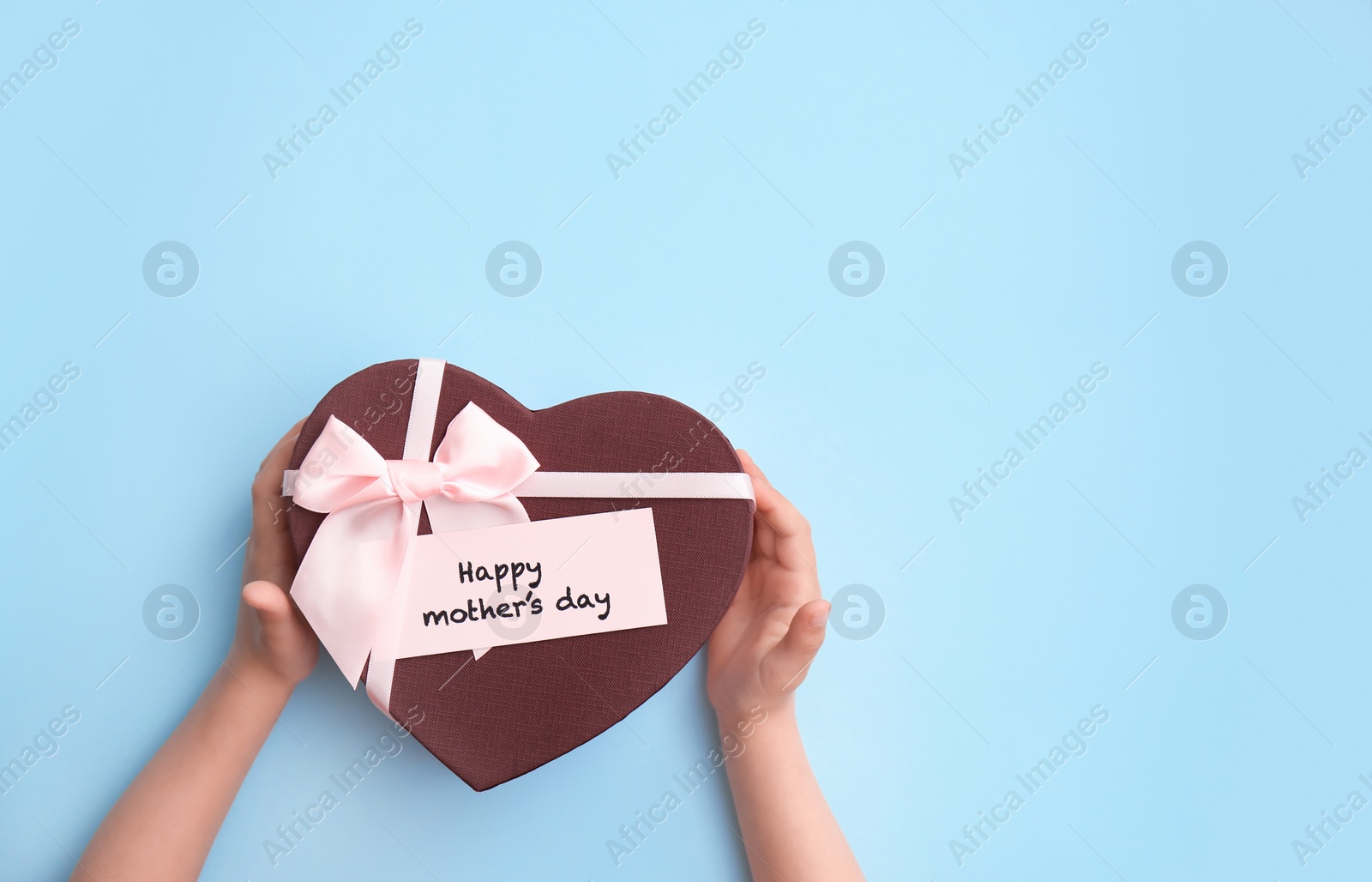 Photo of Child holding gift box for Mother's Day on color background