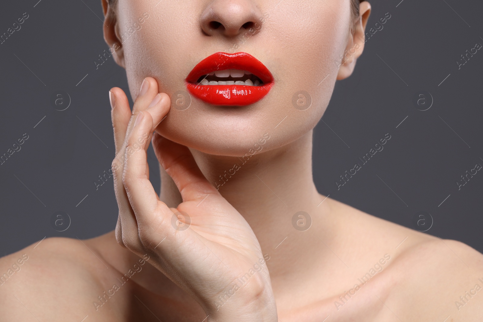 Photo of Young woman with beautiful red lips on grey background, closeup