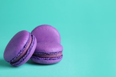 Photo of Delicious purple macarons on turquoise background. Space for text