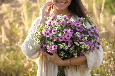 Photo of Woman holding bouquet of beautiful wild flowers outdoors, closeup