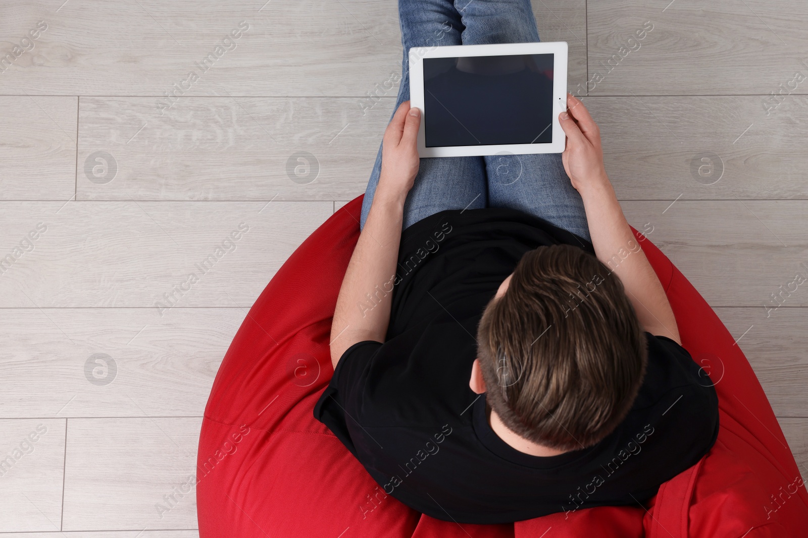 Photo of Man working with tablet in beanbag chair, top view. Space for text