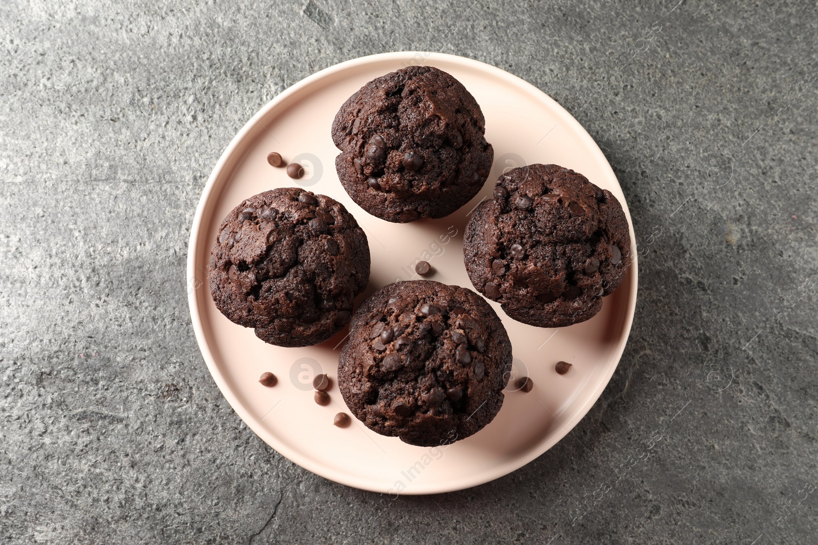 Photo of Delicious chocolate muffins on grey textured table, top view