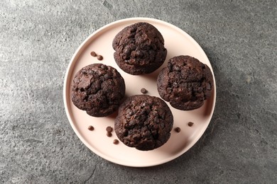Delicious chocolate muffins on grey textured table, top view