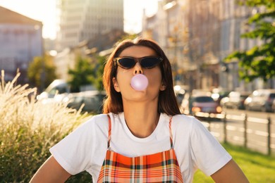 Photo of Beautiful woman blowing gum on city street