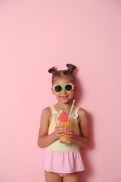 Photo of Cute little girl with glass of cocktail on color background