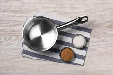 One steel saucepan and spices on white wooden table, top view