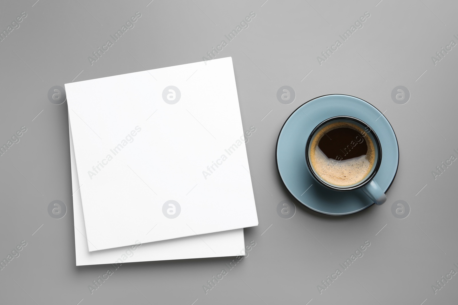 Photo of Blank paper sheets for brochure and cup of coffee on grey background, flat lay. Mock up