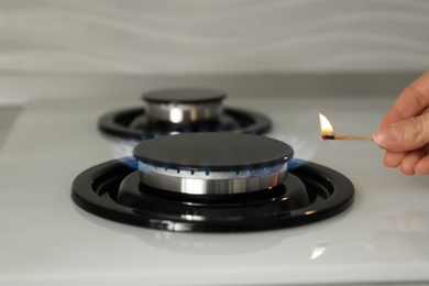 Photo of Woman lighting gas stove with match, closeup