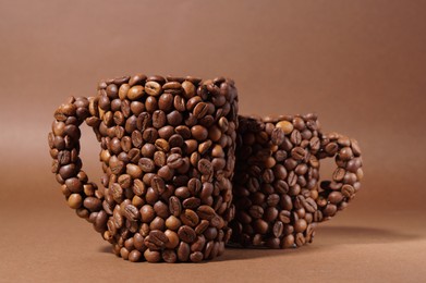 Cups made of coffee beans on brown background