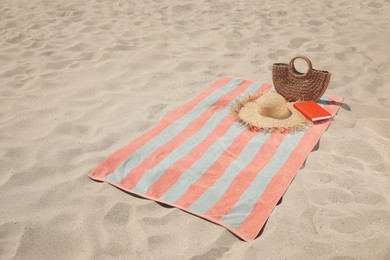 Beach towel with bag, hat and book on sand