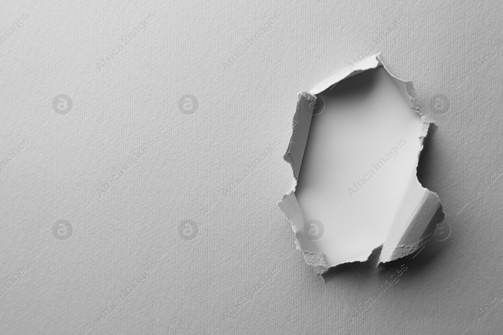 Photo of Hole in white paper on light background, space for text