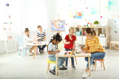 Photo of Children with female teacher at painting lesson indoors