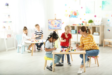 Children with female teacher at painting lesson indoors