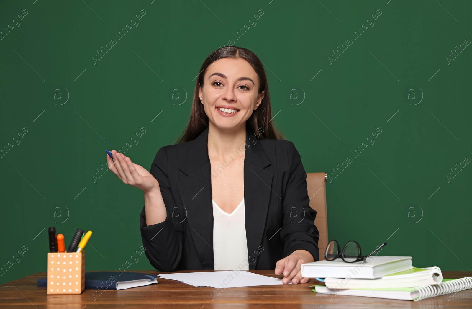 Photo of Portrait of young teacher at table against green background