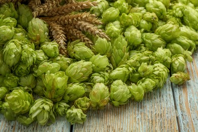 Photo of Fresh green hops and spikes on light rustic table, closeup