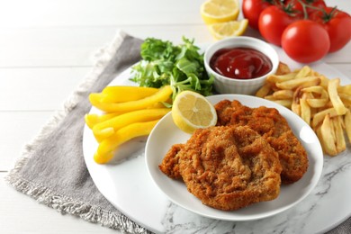 Photo of Tasty schnitzels served with potato fries, ketchup and vegetables on white wooden table, closeup