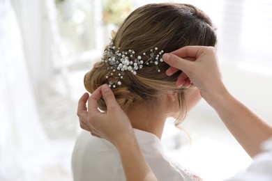 Photo of Professional stylist making wedding hairstyle for bride in salon, back view