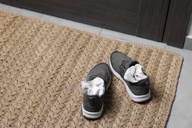 Photo of Sneakers with dirty socks on woven mat indoors, closeup. Space for text