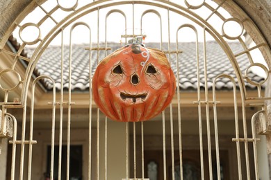 Photo of Pumpkin lantern on white fence outdoors. Halloween decoration