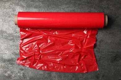 Photo of Roll of red plastic stretch wrap on grey stone background, top view
