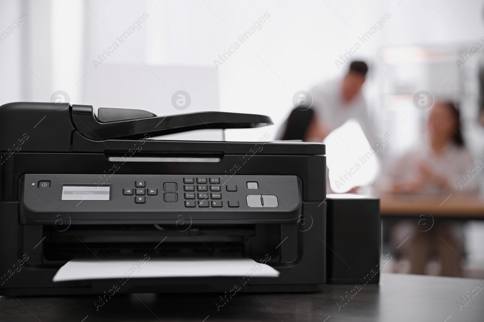 Photo of New modern printer on table in office. Space for text