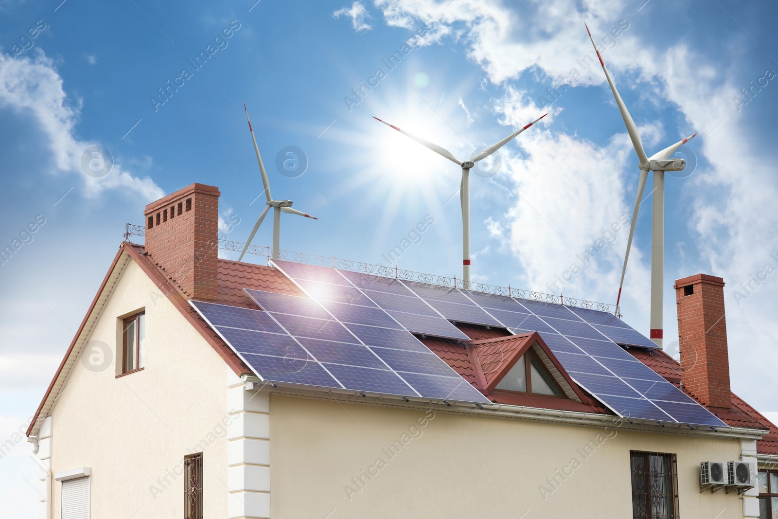 Image of Wind turbines near house with installed solar panels on roof. Alternative energy source