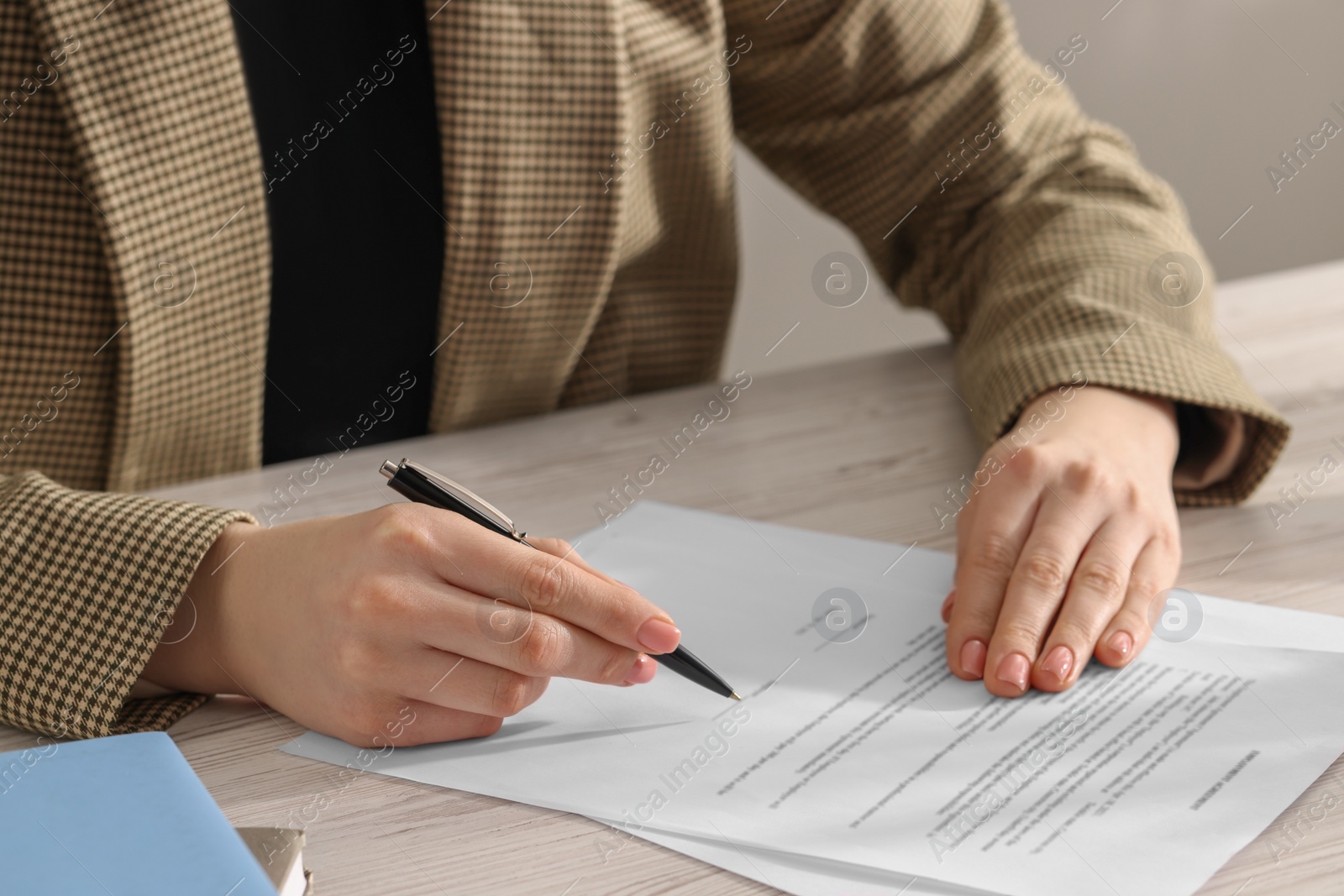 Photo of Woman signing document at wooden table, closeup