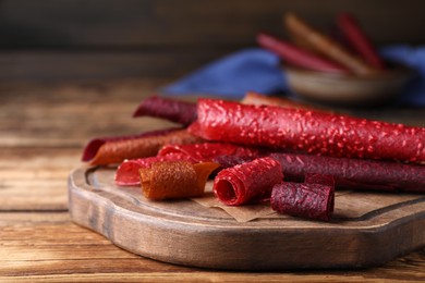 Delicious fruit leather rolls on wooden table, closeup