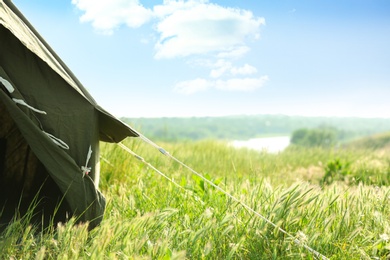 Camping tent in green field on sunny day. Space for text