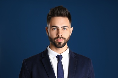 Portrait of handsome young man in office suit on color background