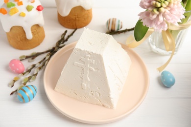 Photo of Traditional cottage cheese Easter paskha and eggs on white wooden table