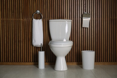 Photo of Simple bathroom interior with new toilet bowl near wooden wall
