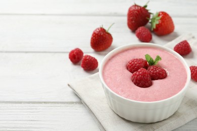 Delicious berry mousse with mint on white wooden table, space for text