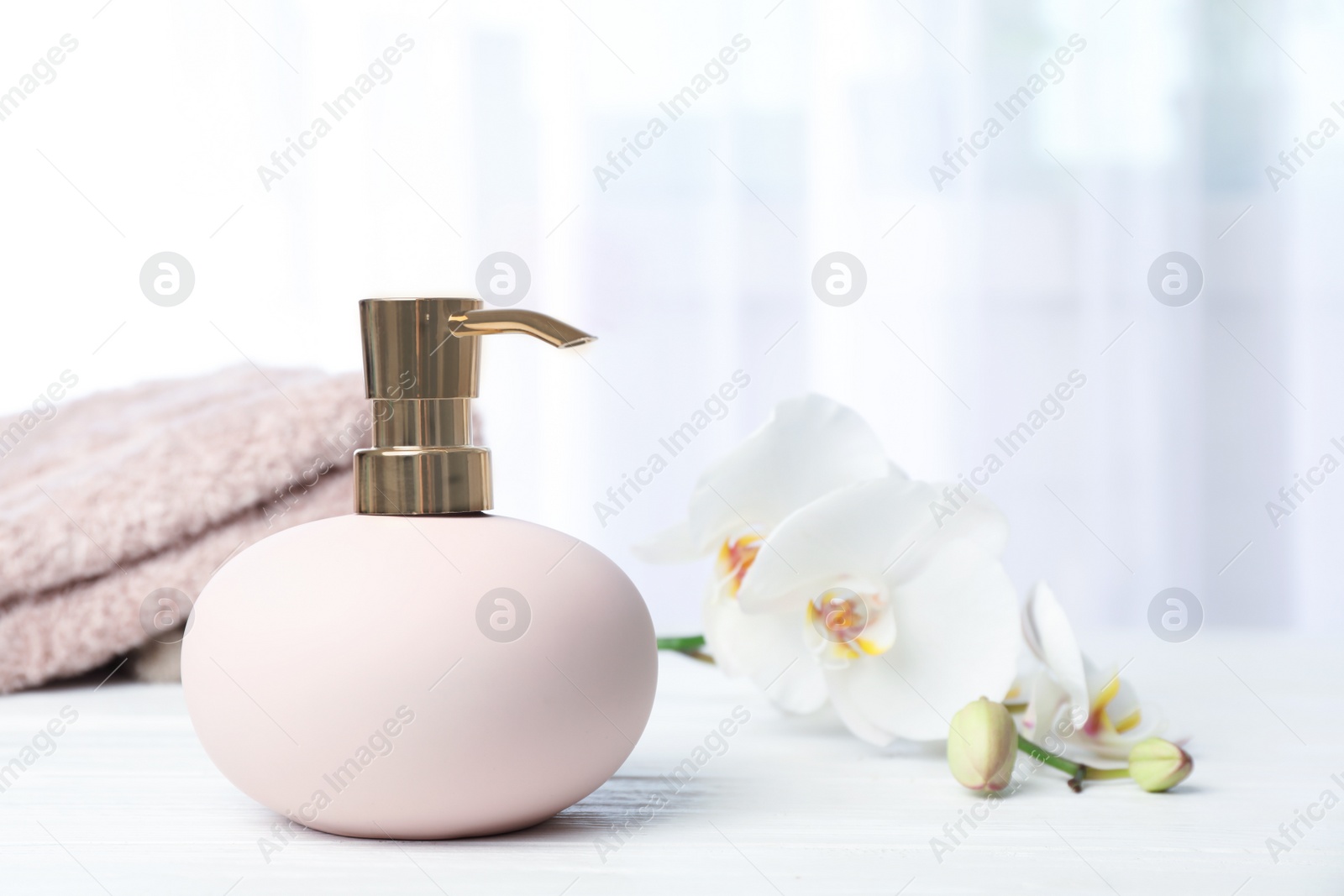 Photo of Stylish soap dispenser with flowers and towels on table. Space for text