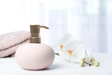 Photo of Stylish soap dispenser with flowers and towels on table. Space for text