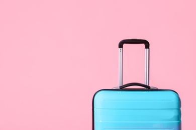 Photo of Modern blue suitcase on light pink background. Space for text