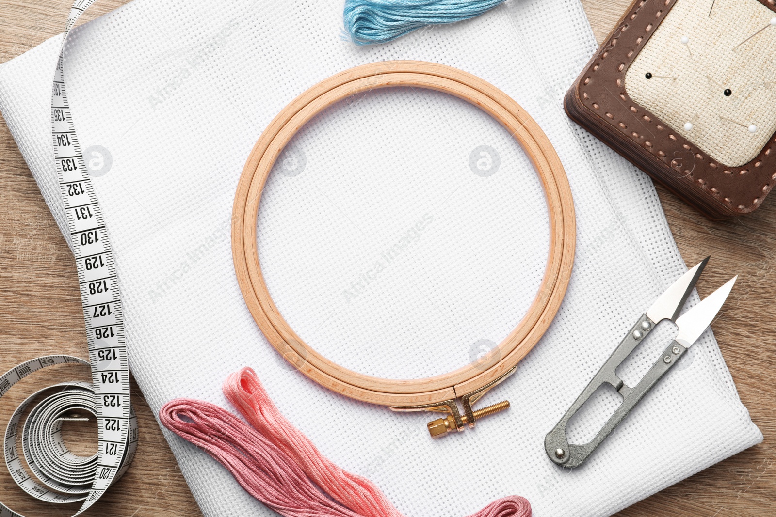 Photo of Set of embroidery equipment on wooden table, flat lay