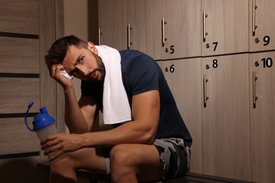 Handsome tired man with shaker in locker room