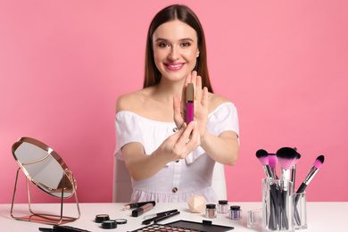 Beauty blogger showing lipgloss on pink background