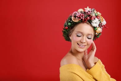 Photo of Beautiful young woman wearing Christmas wreath on red background. Space for text