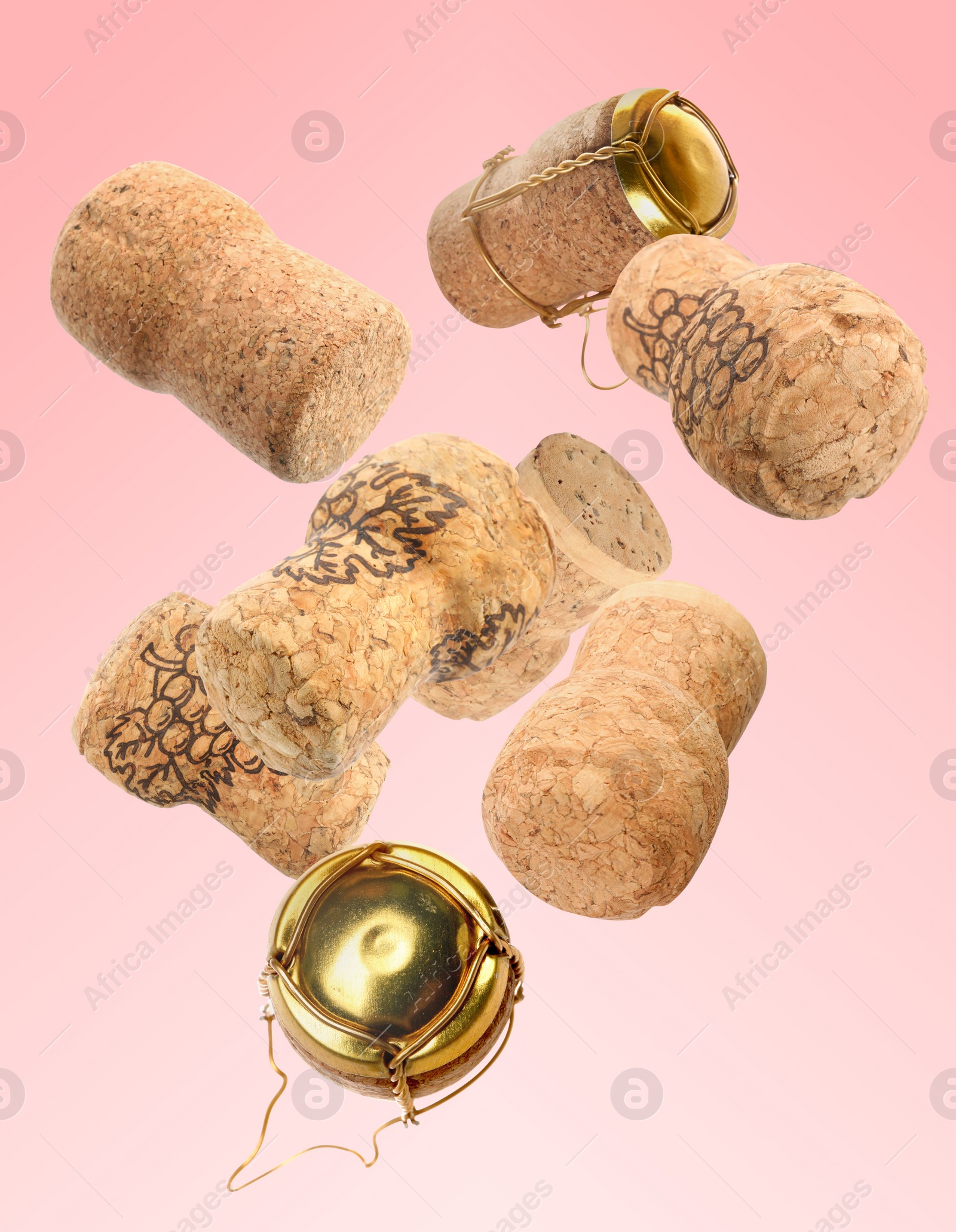 Image of Many corks of sparkling wine bottles falling on pink background