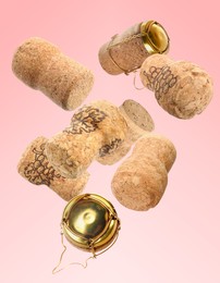 Image of Many corks of sparkling wine bottles falling on pink background