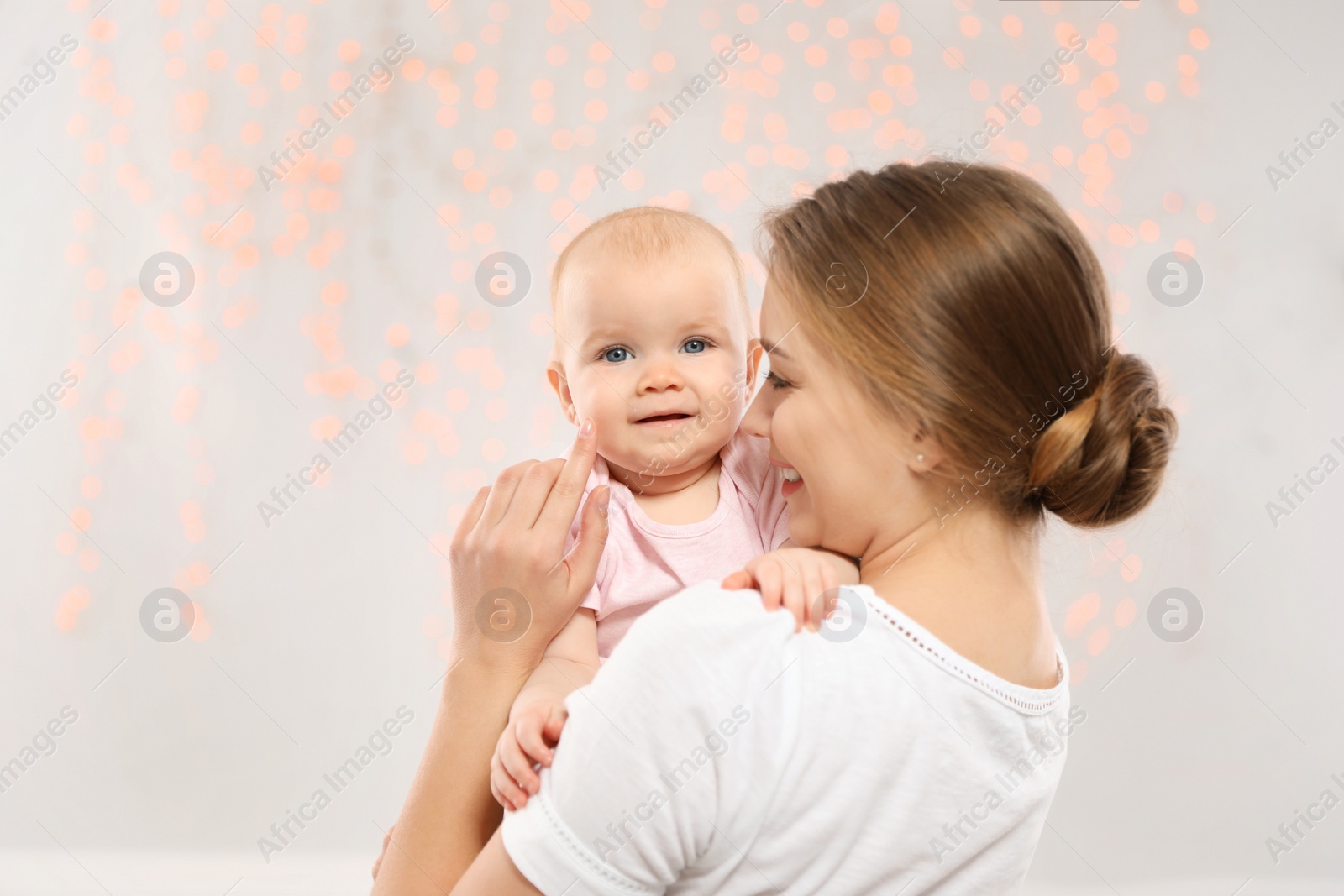 Photo of Portrait of happy mother with her baby against blurred lights