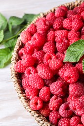 Tasty ripe raspberries in wicker basket on table, closeup