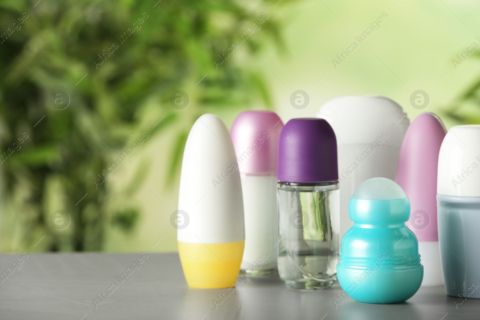 Photo of Different deodorants on white wooden table against blurred background