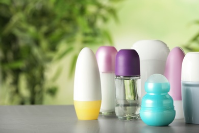 Photo of Different deodorants on white wooden table against blurred background