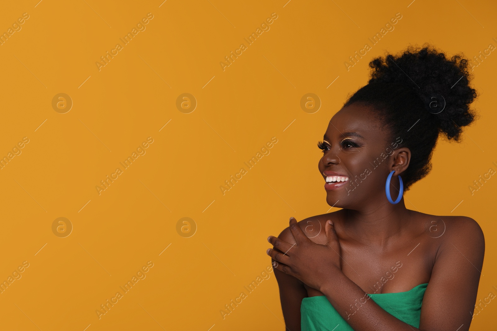 Photo of Fashionable portrait of beautiful happy woman with makeup on orange background, space for text