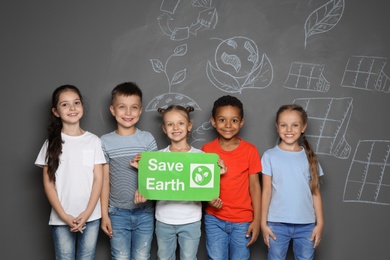 Photo of Little school children with placard SAVE EARTH and drawings on grey background